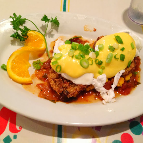 Fried green tomato benedict with poached eggs, fried green tomatoes, spinach, hollandaise, and roasted tomato sauce on toasted cornbread