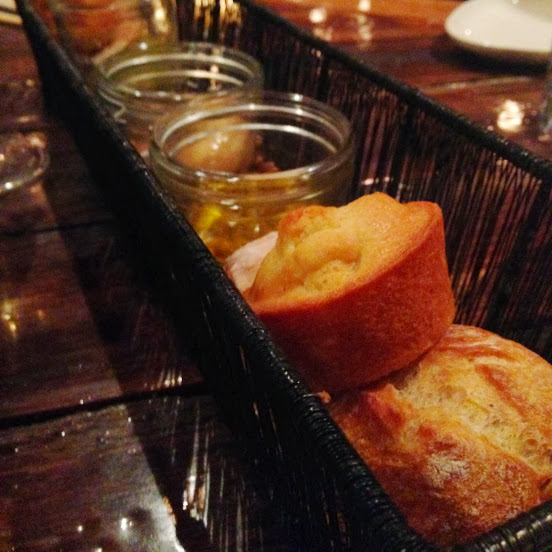 Bread basket with assorted breads, house pickles, honey butter, and tomato-herb oil