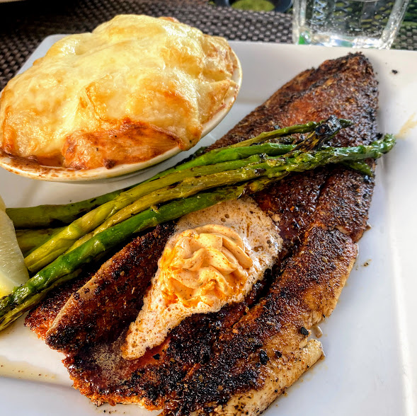 Blackened Baileys Harbor Fish Company Lake Michigan whitefish, New Orleans-style with spicy Cajun compound butter, au gratin potatoes, and asparagus, Harbor Fish Market & Grille