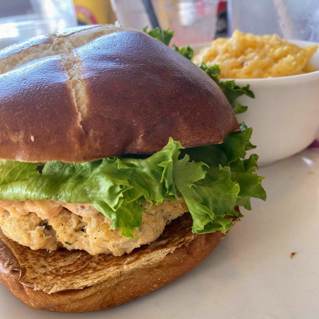 Maryland-style lump crab cake sandwich with pimento cheese and side of stone ground grits, The Salty Dog Cafe